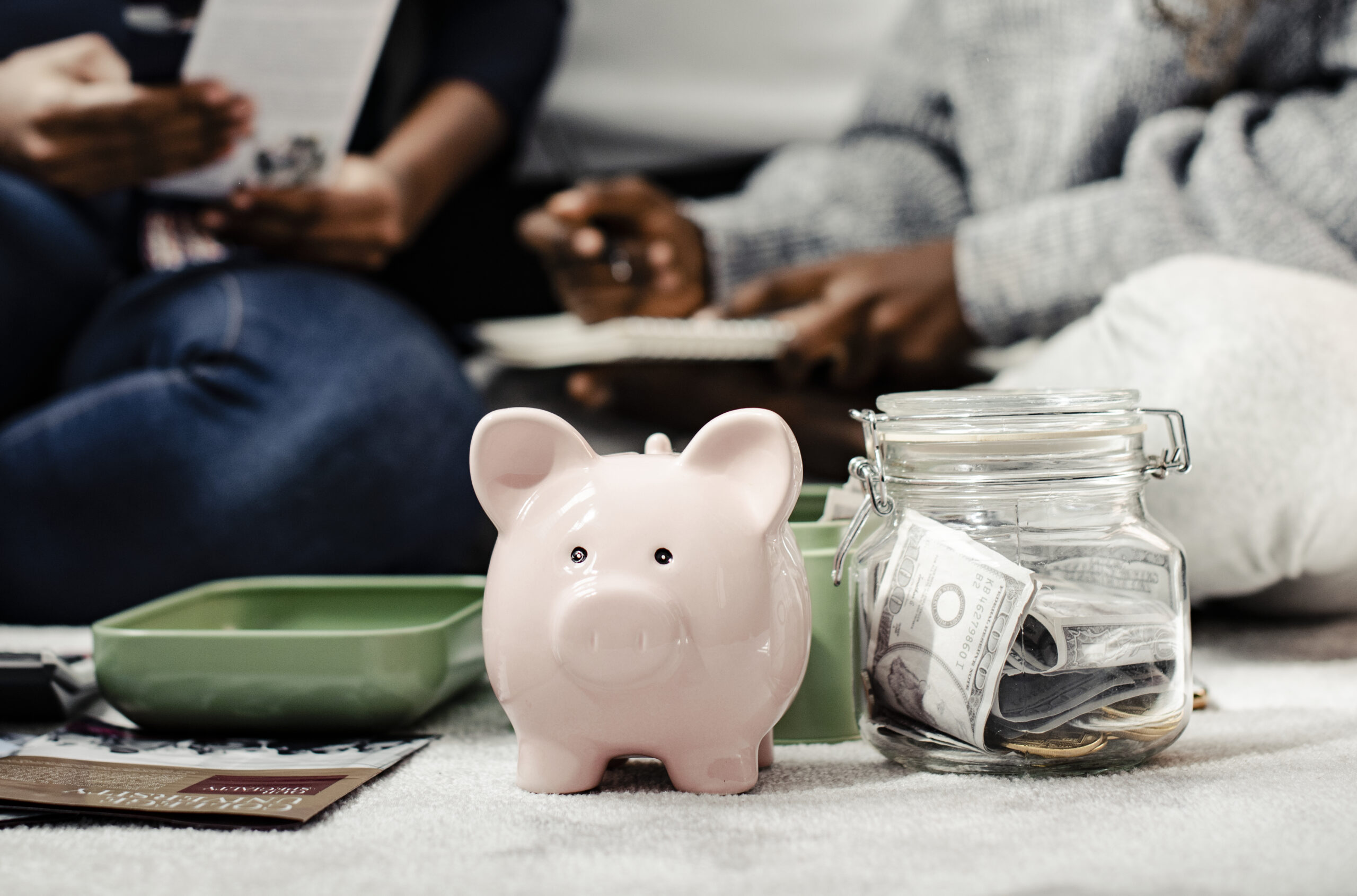 Pesonas organizando cuentas atras y hucha y recipientes con ahorros adelante